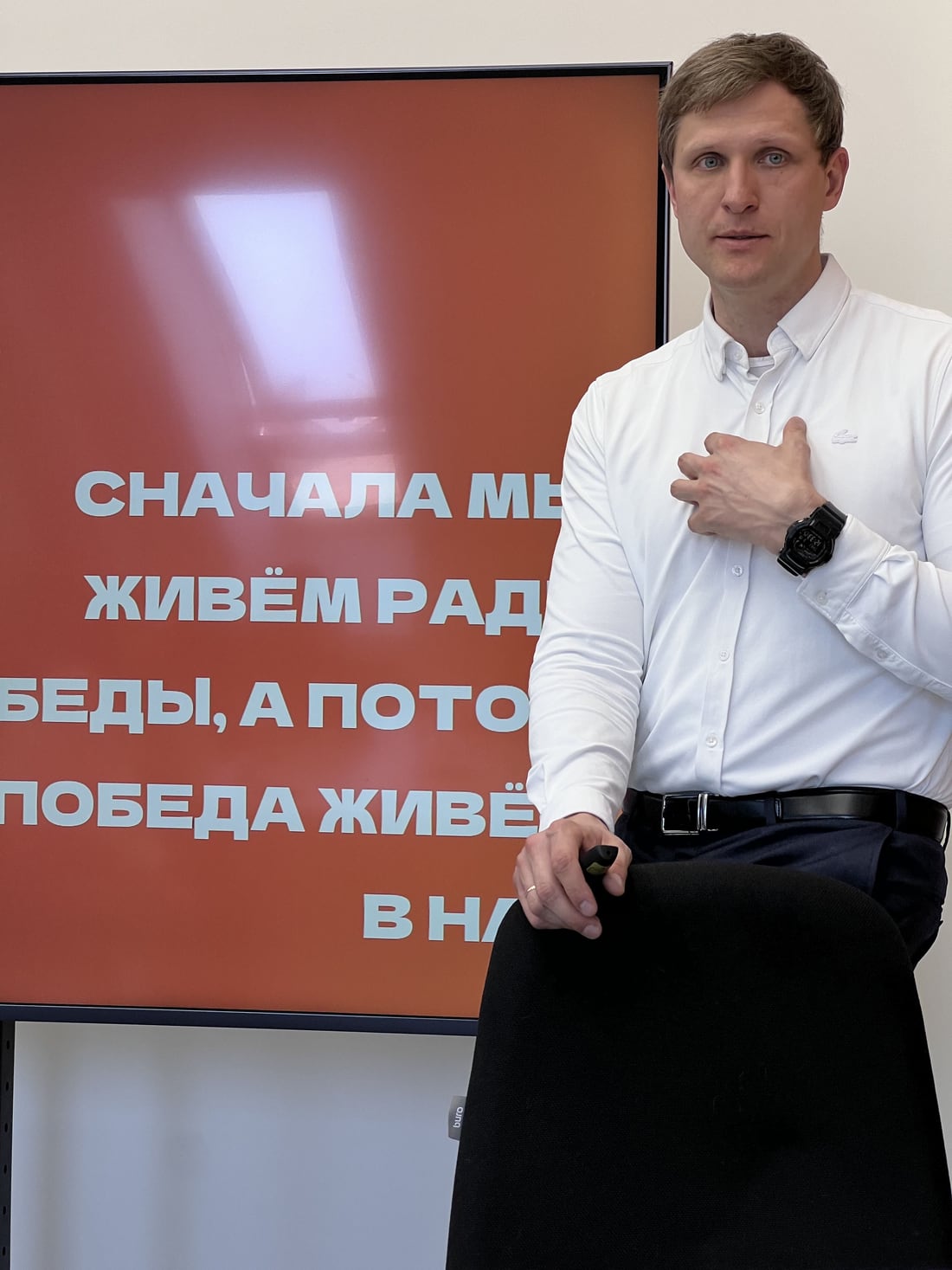 Слайд на сессии с надписью «Сначала мы живём ради победы, а потом победа живёт в нас», перед экраном выступающий